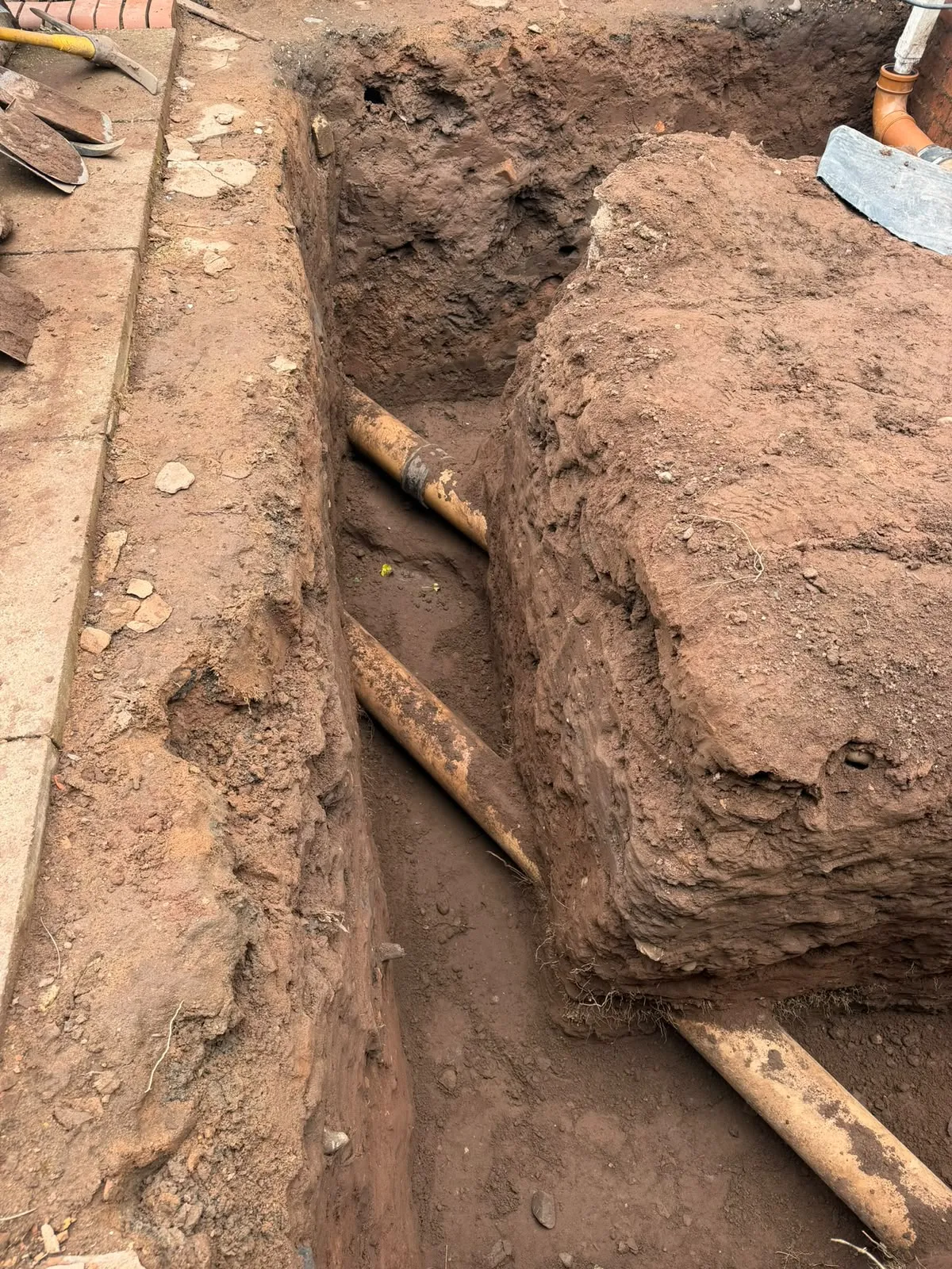 Excavated footing trench in Wightwick with two large drain pipes crossing it diagonally