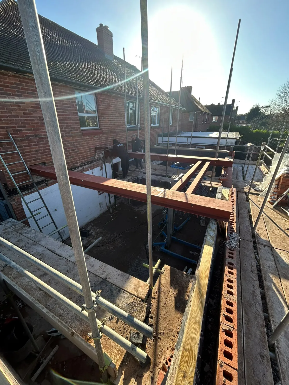 Large red steel beams of the H-frame spanning the open ground floor