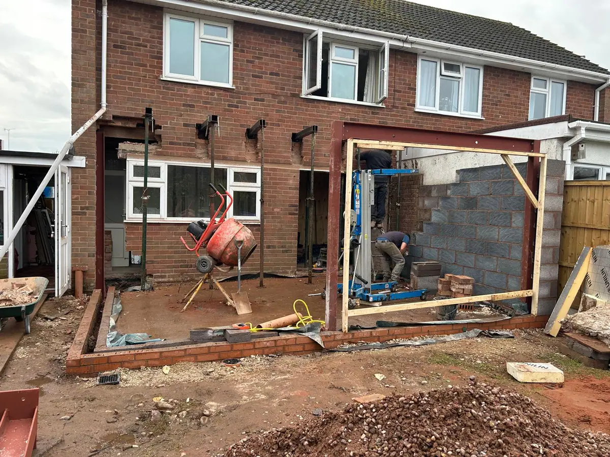Blockwork walls rising around a steel frame with acrow props supporting the existing house
