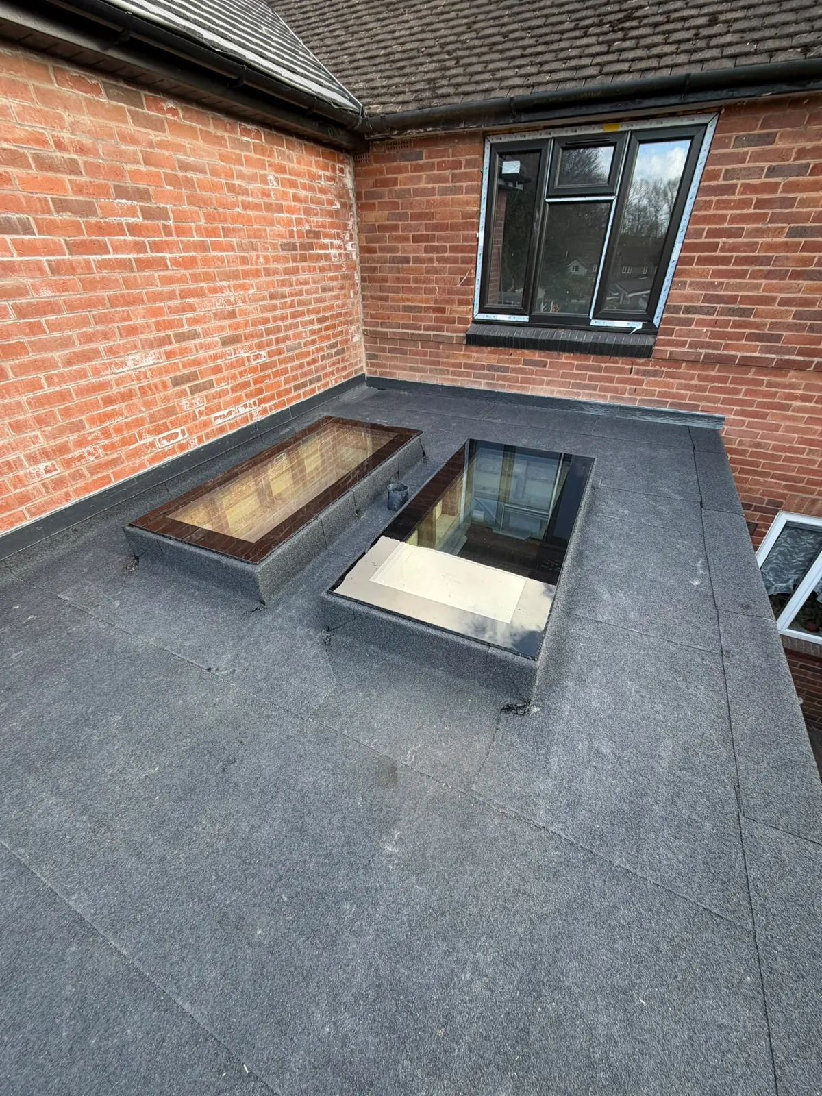 Flat roof membrane with a rooflight beside the house wall