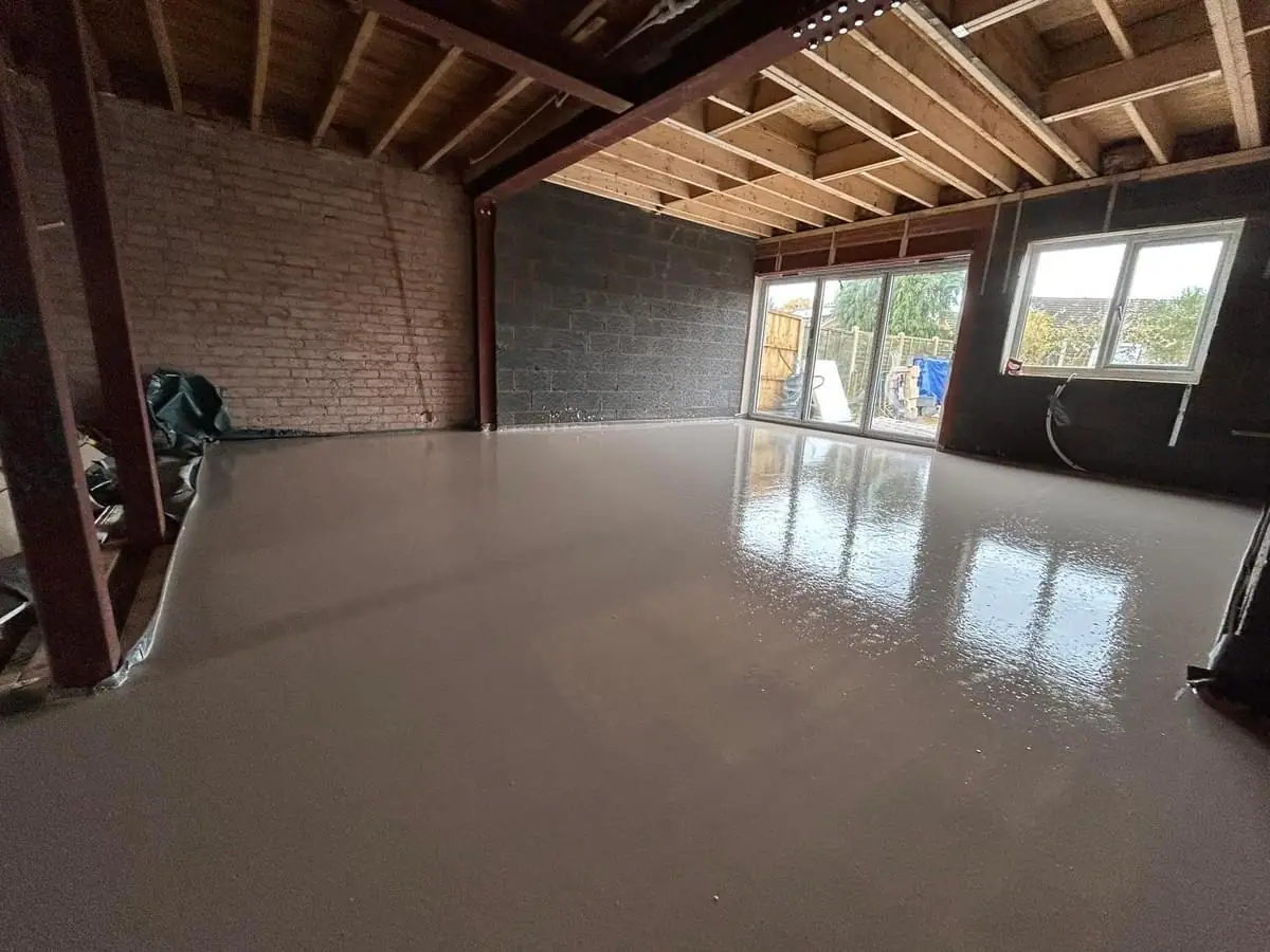 Freshly laid liquid screed floor in an open plan extension with steel beams overhead